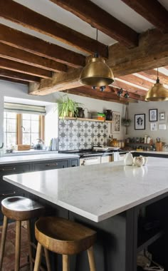 a kitchen with two stools and an island in the middle, surrounded by wood beams