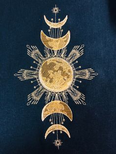 an embroidered sun and moon design on a dark blue shirt with gold threadwork in the middle