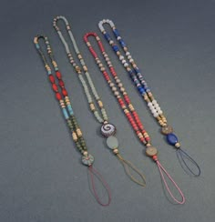 four necklaces with different colored beads on them