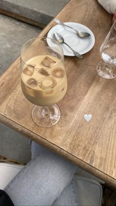 a person sitting at a wooden table with two glasses on it and one glass filled with liquid