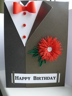 a happy birthday card with a red flower and bow tie on the back of it