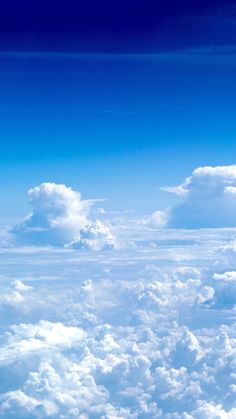 the view from an airplane looking down on clouds and blue sky with white fluffy clouds