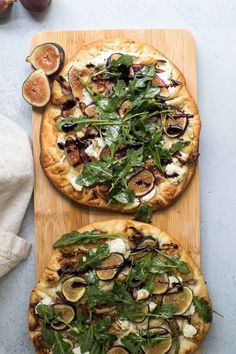 two pizzas sitting on top of a wooden cutting board