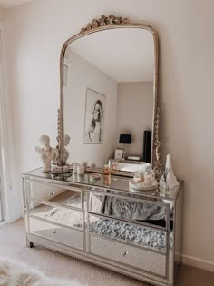 a mirror sitting on top of a dresser next to a white rug in a room