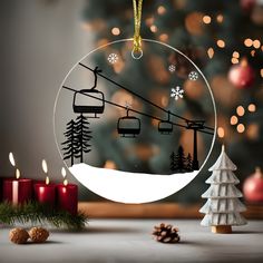 a christmas ornament with a ski lift in the background and candles around it