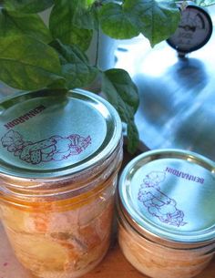 two jars filled with food sitting on top of a table next to a potted plant