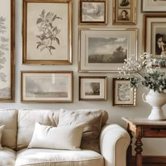 a living room filled with furniture and pictures on the wall next to a vase full of flowers