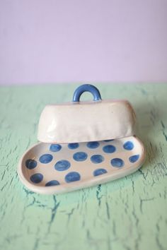 a blue and white polka dot dish sitting on top of a green table with purple wall behind it