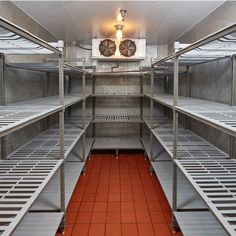 rows of metal shelves with red flooring in a large room filled with lots of windows