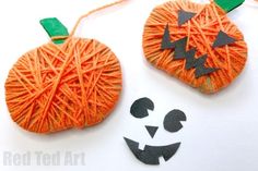 two pumpkins made out of yarn with faces drawn on the string and one has a green nose