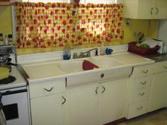 a kitchen with white cabinets and yellow curtains on the window sill above the sink