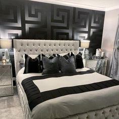 a large bed with black and white pillows on it's headboard in a bedroom