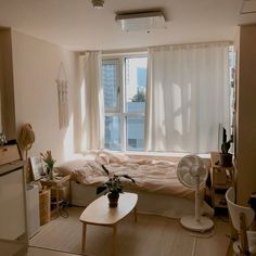 a living room with a couch, coffee table and fan in front of a window