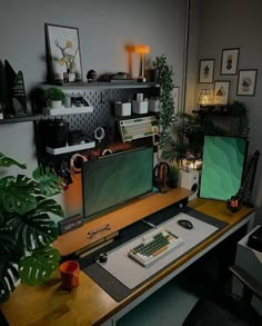 a computer desk with two monitors and a keyboard on it, in front of a potted plant