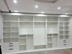 an empty room with white shelves and drawers in the center, all lined up against the wall