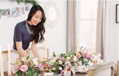 a woman setting a table with flowers and candles