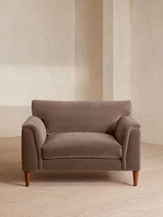 a couch sitting on top of a hard wood floor next to a white wall in an empty room