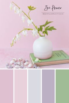 a white vase filled with flowers on top of a pink table next to a book