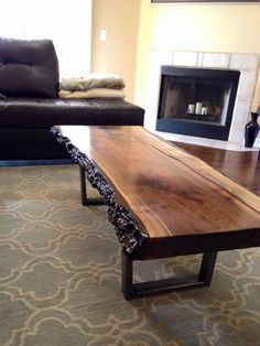 a wooden table sitting in the middle of a living room next to a black couch