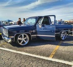 a blue truck with chrome rims parked in a parking lot next to other vehicles