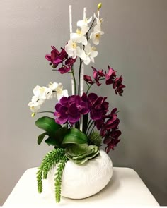 a white vase filled with purple and white flowers