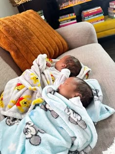 two babies wrapped in blankets on a couch