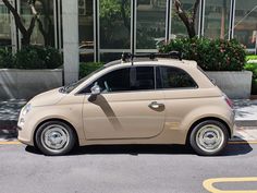 a small beige car parked on the side of the road in front of a building