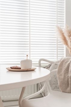 a white table and chairs in a small room with blinds on the window sill