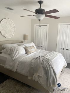 a bedroom with a bed, ceiling fan and two closets in the background that have white doors