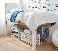 a white bed sitting under a window next to a chair and table with two drawers