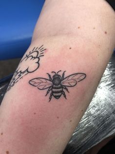 a small black and white bee tattoo on the arm