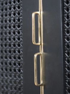 a close up of a metal door handle on a black cabinet with chains hanging from it