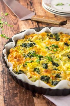 a quiche with cheese and spinach in a pie pan on a wooden table