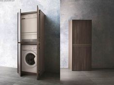 an empty washer sitting next to a wooden cabinet in a room with concrete walls