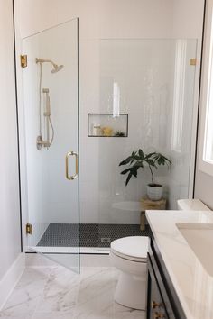 a bathroom with a glass shower door and white tile flooring, along with a toilet and sink