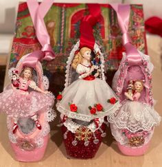 three little dolls are sitting in baskets on a table next to a box with pink ribbon