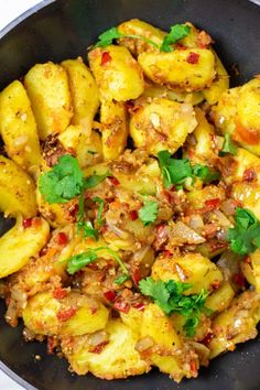 a pan filled with potatoes and meat covered in cilantro, parsley and seasoning