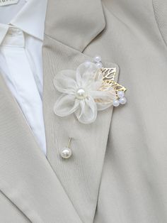 a man wearing a suit and tie with a flower brooch on his lapel