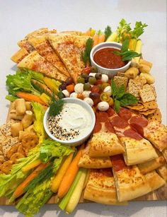 a pizza platter with many different types of food on it, including vegetables and dips