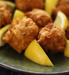 some food is sitting on a plate with lemon wedges and meatballs in it