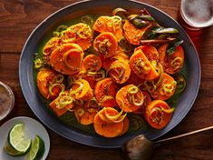 a plate full of sliced up peppers and limes next to two glasses of beer