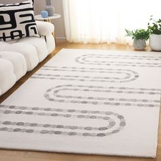 a living room area with a white rug on the floor and black and white pillows