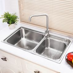 stainless steel kitchen sink with drainer and faucet, in front of window