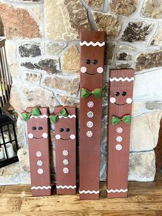 three wooden sticks with faces and bows on them sitting in front of a stone wall