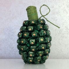 a green pine cone filled with chocolates on top of a white table next to a gray wall