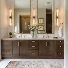 a bathroom with double sinks and large mirrors on the wall, along with a rug in front of it