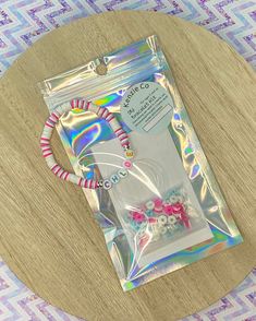 the package is wrapped in holographic paper and sits on top of a wooden table