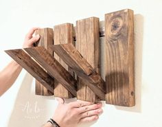 two hands are holding pieces of wood on the wall