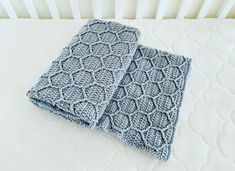 two crocheted dishcloths sitting on top of a white bed next to each other