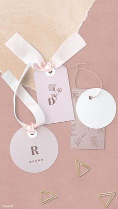 some white tags with pink bows and gold letters on them are laid out next to each other